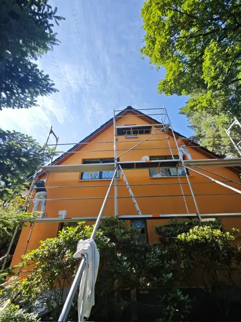 Orangefarbene Hausfassade mit Gerüst nach dem Fassadenanstrich
