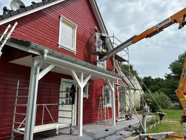 Rote Holzfassade während sorgfältiger Fassadenarbeiten